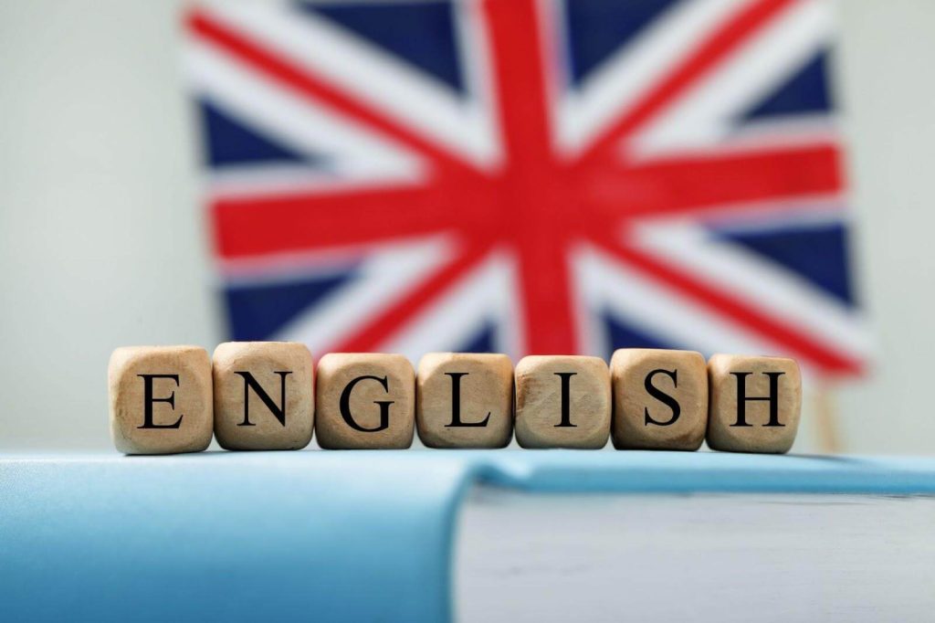 Bandeira britânica ao fundo com a palavra english escrita com cubinhos