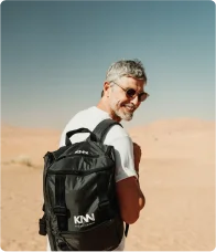 Ator Reynaldo Gianecchini de óculos e camiseta branca no deserto com mochila KNN Idiomas