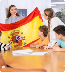 Crianças e professora em sala de aula presencial com a bandeira da espanha